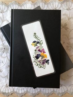 a bookmark with flowers on it sitting on top of a lace covered table cloth