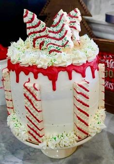 a large white cake decorated with candy canes and icing on a table in front of a christmas tree