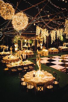 an outdoor event with tables and chandeliers