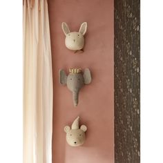 three stuffed animals are hanging on the wall in front of a pink wall with curtains