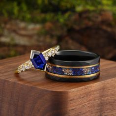 two rings with blue and gold designs on them sitting on top of a wooden table