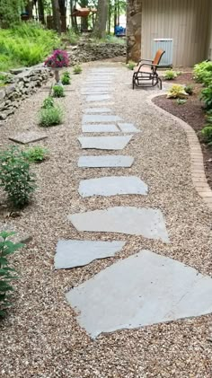 a stone path in the middle of a graveled area next to a wooden bench