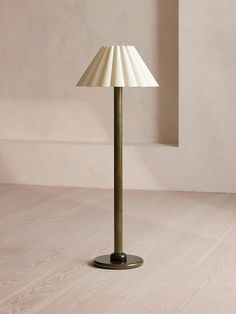 a lamp that is on top of a wooden floor in front of a white wall