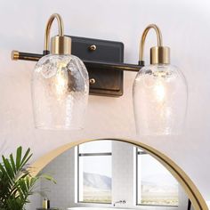 a bathroom vanity light with two clear glass globes hanging from it's side