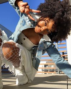 a woman with an afro is posing for the camera and holding her hand on her hip