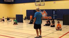 a group of people sitting and standing on top of a gym floor next to each other