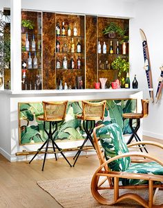 a tropical themed bar with wicker chairs and bottles on the back wall, along with palm leaves