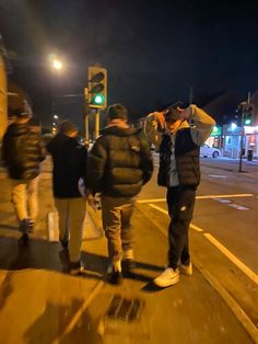 people walking down the street at night with one person taking a picture on his cell phone