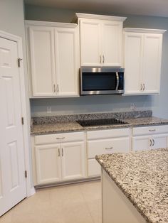 a kitchen with granite counter tops and white cabinets