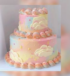 there is a three layer cake with clouds and stars on the top it has pink icing