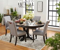 a dinning room table with chairs around it in front of a window and potted plants