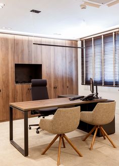 an office desk with two chairs and a computer monitor on top of it in front of a wooden wall