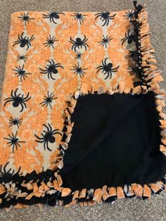 an orange and black spider blanket on the floor