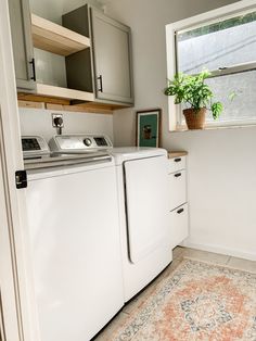 a white washer and dryer sitting in a kitchen next to a window with potted plants