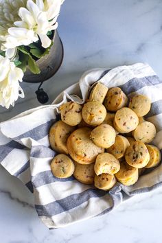 a bowl filled with cookies on top of a white and blue towel next to flowers