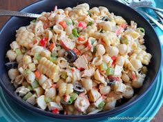 a bowl filled with pasta salad on top of a blue plate next to silverware