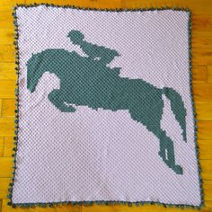 a crocheted blanket with a silhouette of a horse and rider on the back