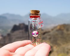 a hand holding a tiny glass bottle filled with confetti