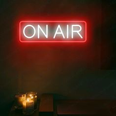 a neon sign that reads on air next to some candles