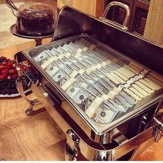 a tray with money sitting on top of a counter next to berries and chocolate cake