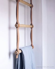 a wooden ladder hanging from the side of a wall next to a blue towel rack