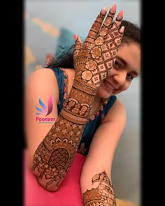 a woman with henna on her hands and arm is smiling at the camera while she holds