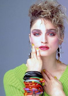 a woman with bright makeup and bracelets on her hand is posing for the camera