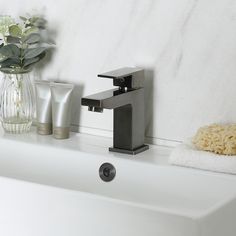 a bathroom sink with soap, toothpaste and flowers in vases on the counter