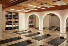 an empty yoga room with rows of mats on the floor and shelves full of bottles