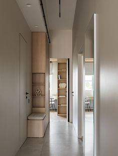 an empty hallway leading to a dining room and living room with open shelving on the wall