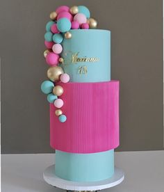 a three tiered cake with pink, blue and gold decorations