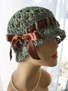 a mannequin head wearing a green crochet hat with a bow on it