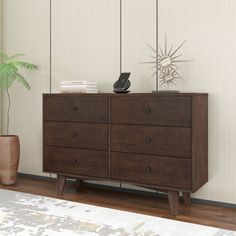 a brown dresser sitting next to a plant in a room