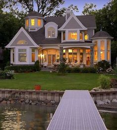 a large white house sitting on top of a lush green field next to a lake