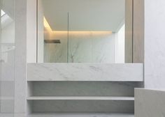 a bathroom with marble walls and flooring, along with a large mirror on the wall