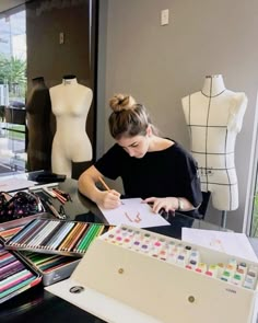 a woman sitting at a table with lots of art supplies