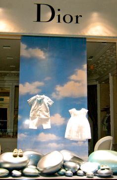 a display in a store window with baby clothes and rocks on the ground next to it