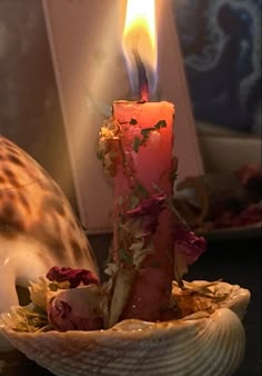 a lit candle sitting in a shell on top of a table