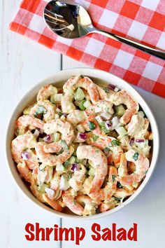 a white bowl filled with shrimp salad on top of a red and white checkered table cloth