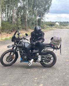 a person on a motorcycle wearing a helmet and goggles sitting in the middle of the road