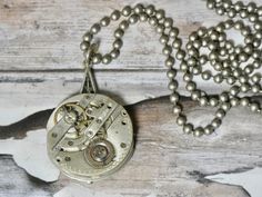 This is a vintage watch movement, just the gears. It doesn't work its just for the beauty of the inside of old watches. A conversation piece. Authentic antique/vintage pocket watch movement. Great piece for your steampunk look. I T E M ∙ S P E C I F I C A T I O N S - NECKLACE: 28" stainless steel bead ball chain - PENDANT: Watch gears are 1 1/8" round, backing is glued and makes the pendant 1 1/2" long C A R E ∙ T I P S We don’t want your special moment to fade. To maintain the quality of your j Watch Gears, Pendant Watch, Bead Ball, Vintage Pocket Watch, Old Watches, Watch Movement, Chain Pendant, Watch Necklace, Ball Chain