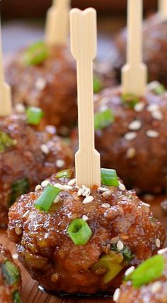 some meatballs with toothpicks in them sitting on a wooden board and ready to be eaten