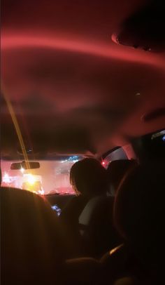 people in the back seat of a car at night with lights shining on their windows