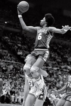 a basketball player jumping up in the air to dunk a ball while two other players look on