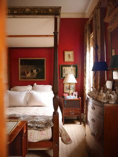 a bedroom with red walls and white bedding