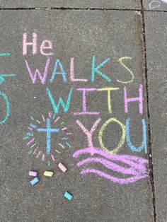 the sidewalk has chalk writing on it that says he walks with you and fireworks in the sky