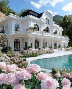 a large white house with lots of windows and flowers in front of the pool area