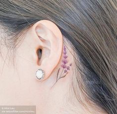 a woman's ear has a small flower tattoo on it