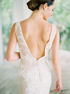 the back of a woman's wedding dress, with her hand on her hip