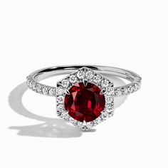 a ring with a red stone surrounded by diamonds